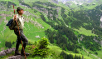 ein Jäger steht mit Wanderstock, Rucksack und Hut vor einer Alpenkulisse.