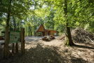 Eine Holzhütte im Wald mit Informationstafel