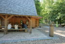 ein Holzhaus in einem Wildpark mit Besuchern unter einem Vordach.