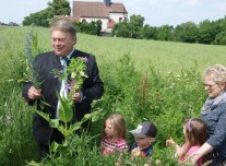 Minister Brunner in einem Feld, Blumen in der Hand, Kinder an der Seite