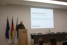 Dr. Friedrich Völk, Jagdverantwortlicher in der Unternehmensleitung Österreichische Bundesforste, spricht am Rednerpult. Daneben läuft eine Powerpoint-Präsentation an der Wand