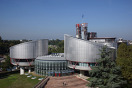 der Europäische Gerichtshof für Menschenrechte von außen. Ein graues aus mehreren Rundbauten bestehendes Gebäude.