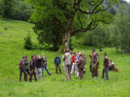 eine Gruppe Menschen steht auf einer Wiese in einer Runde zusammen