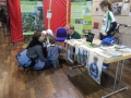 An einem Messestand unterhalten sich Kinder und Erwachsene.