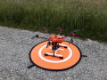 orangene Drohne auf Landeplattform stehend